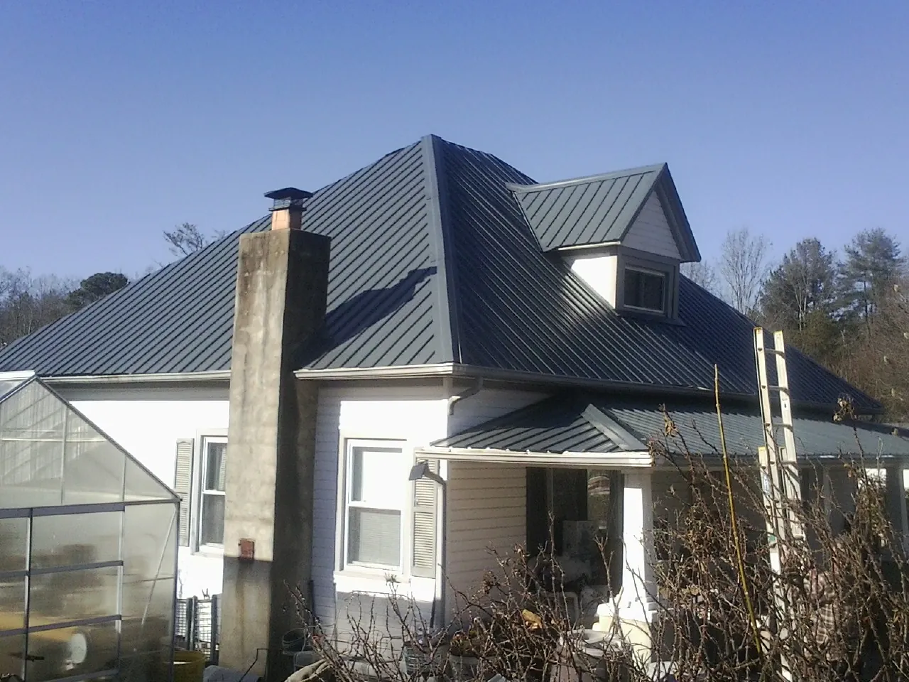 Dark blue standing seam metal roof on a white farmhouse with dormer — Slate & Tile Roof Repair by Roofing Brothers in Queensbury