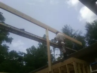Carpenter setting a ridge beam over a new addition frame — Ice Dam Removal by Roofing Brothers in Queensbury