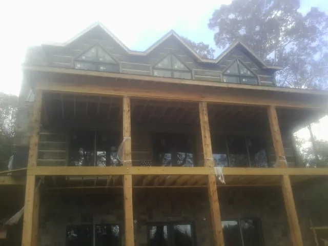 Dormers and porch framing on a large log home under construction — Roof Coating work by our crew in Queensbury