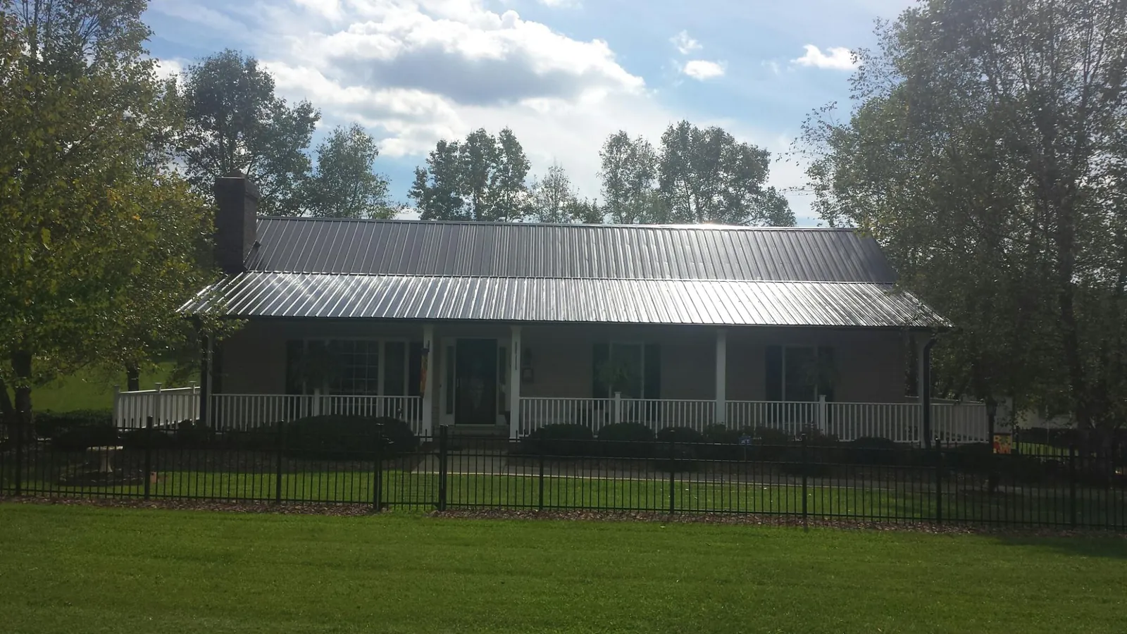 Gray metal roof on a brick ranch with a full width front porch — Gutter Guard Installation work by our crew in Queensbury