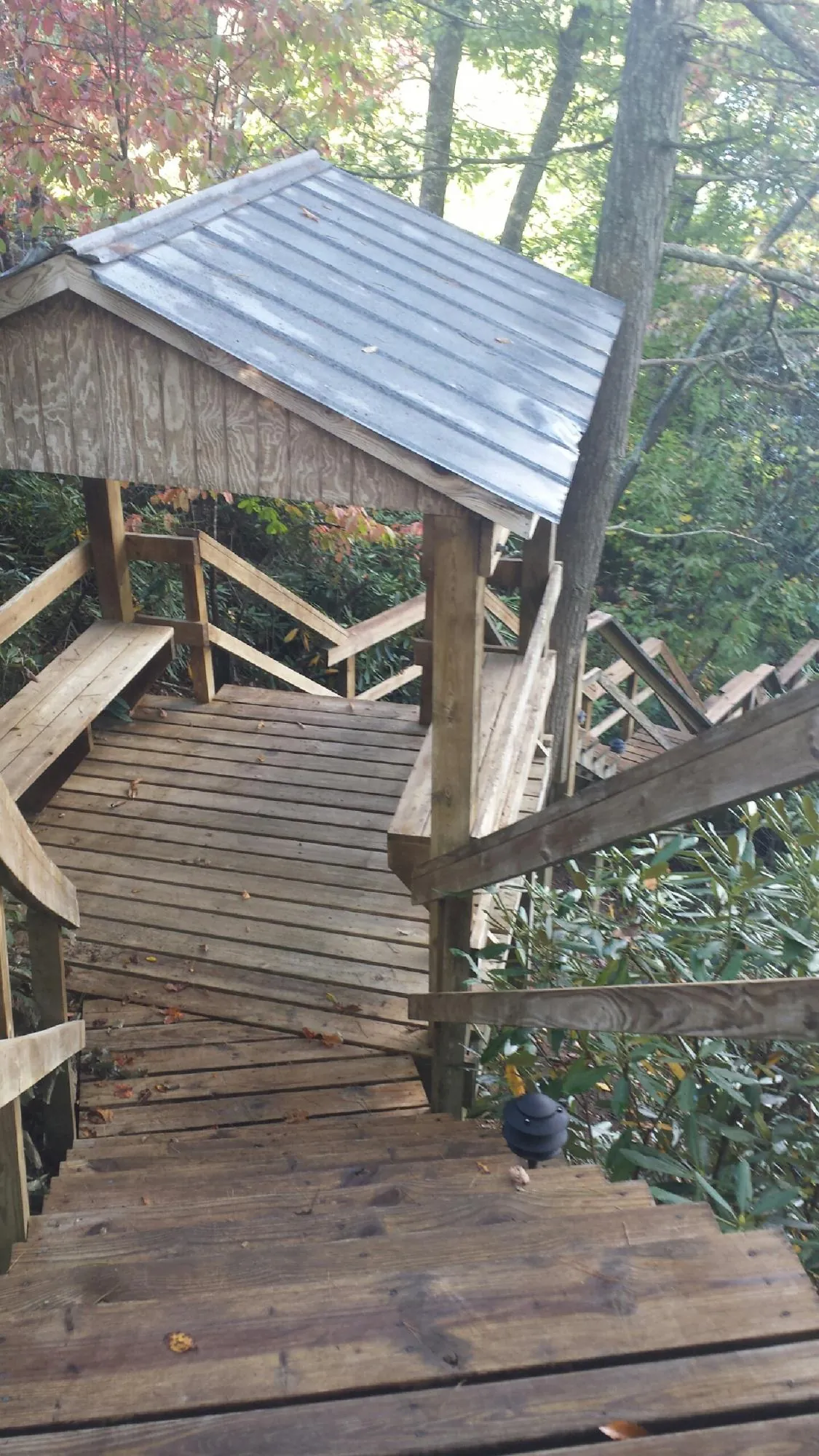 Metal roofed shelter over wooden steps on a wooded walkway — Skylight Repair & Installation work by our crew in Queensbury